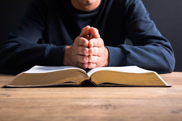istock prayer man hand on Bible 1333246360