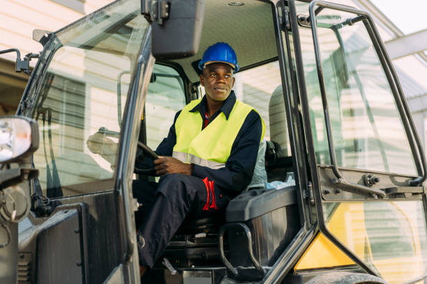Afro-American excavator driver sitting in his machine Young afro excavator driver during his work on construction site bulldozer photos stock pictures, royalty-free photos & images