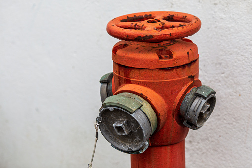 Red fire hose valve opposite white wall. Fire equipment