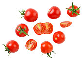 Cherry tomatoes and halves are flying on a white background. Isolated