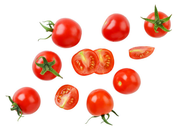 Cherry tomatoes and halves are flying on a white background. Isolated Cherry tomatoes and halves are flying close-up on a white background. Isolated cherry tomato stock pictures, royalty-free photos & images
