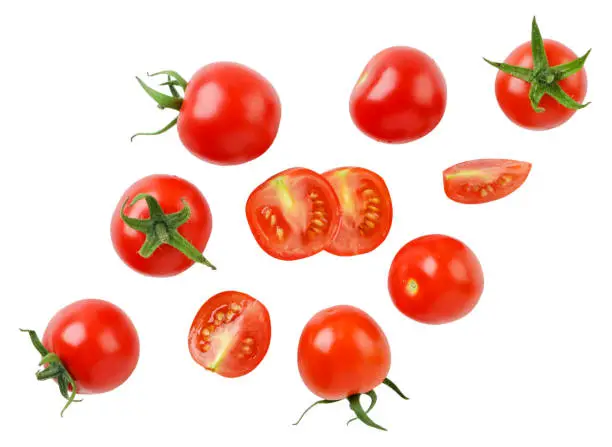Photo of Cherry tomatoes and halves are flying on a white background. Isolated
