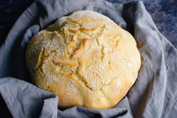 A loaf of crusty French bread wrapped in a cloth napkin