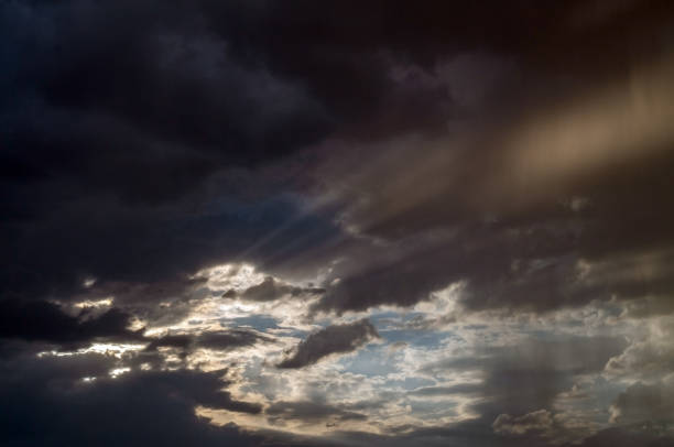 A ray of light through the clouds. Rays of light breaking through dark clouds, a dramatic sky with clouds.Bright sun during the rain.