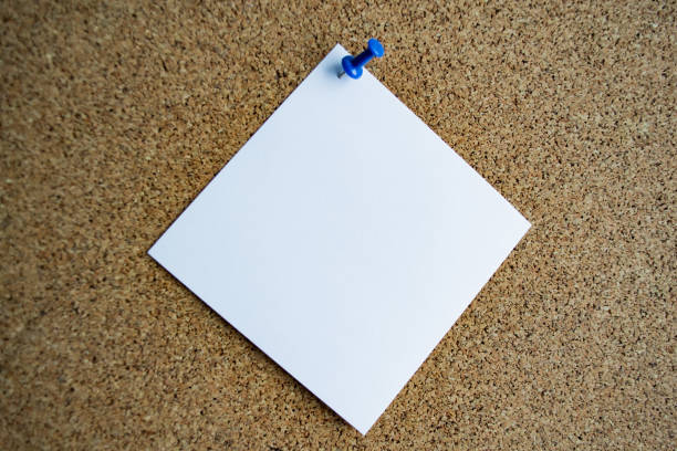 istock A white paper note on a cork board, attached with a blue pushpin. Copy space 1333252461