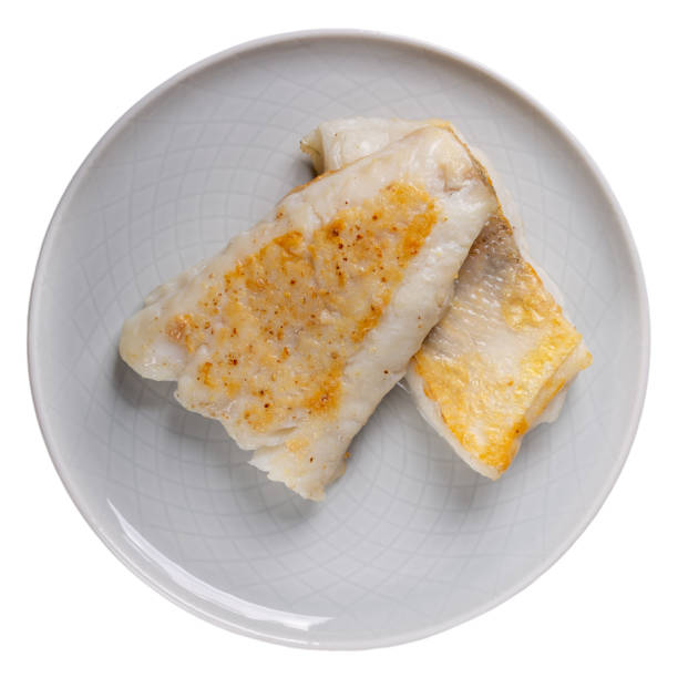 Roasted white fish fillet on gray plate isolated on white background. Top view.