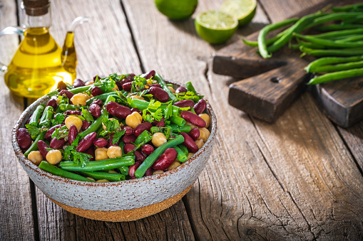 Green beans salad with parsley legumes chickpeas and red beans on rustic wood table background on cutting board, Lebanese recipe with olive oil, Mediterranean diet