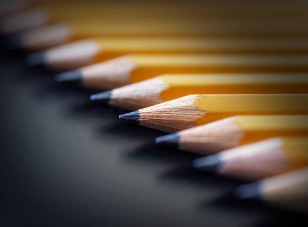 istock A row of yellow pencils arranged in a diagonal on a black background. 1333260756
