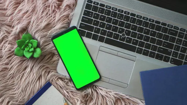 Photo of Mobile phone with green screen on a laptop.