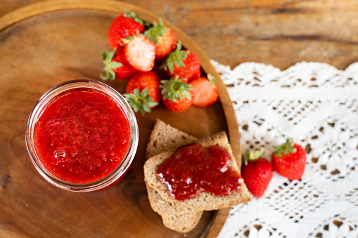 Strawberry jam in a pot, baked on bread & strawberries in a rustic setting.