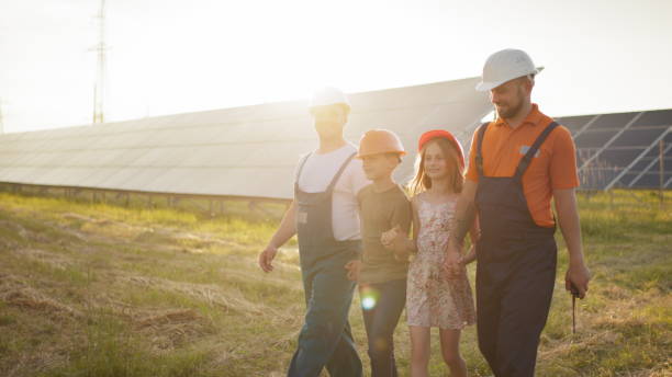 dos padres llevaron a sus hijos al trabajo. dos empleados de una planta de energía solar cuentan a los niños sobre la producción de electricidad. parque solar. concepto de energía alternativa. construcción ecológica - solar energy solar power station student alternative energy fotografías e imágenes de stock