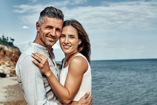 istock Happy middle aged couple laughing and hugging on the beach. 1333263331
