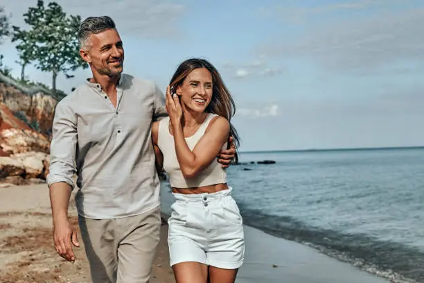 Photo of Happy attractive couple walking on beautiful sunny beach.