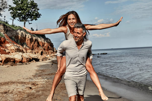 istock Handsome man having wife a piggyback on the beach. 1333263340