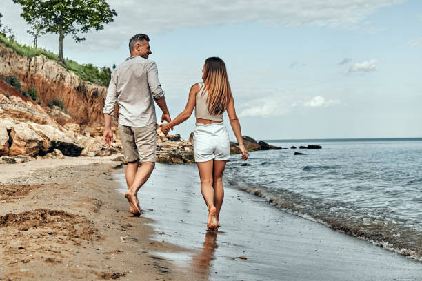 istock Back view of happy middle aged couple walking on a deserted beach. 1333263342