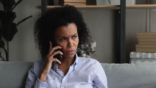 Unhappy african american young woman holding unpleasant cellphone call conversation.