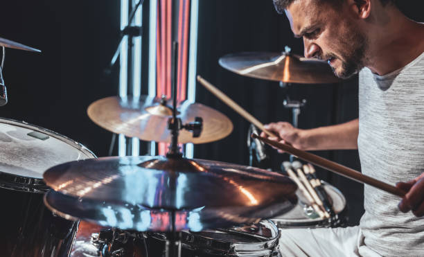 The drummer using sticks while playing on drums during performing. The drummer plays with beautiful lighting on a blurred background. drummer stock pictures, royalty-free photos & images