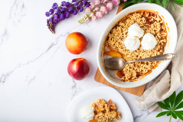 crumble di nettarina fresca con gelato alla vaniglia in forma ceramica su sfondo marmo bianco - cobbler peach dessert fruit foto e immagini stock