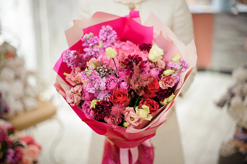 Close-up of amazing bouquet of various fresh flowers wrapped in bright pink paper. Floral shop concept. Flowers delivery.