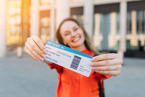 Chica caucásica alegre sosteniendo un boleto aéreo para el avión y el viaje en sus manos photo