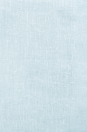 Frosty light blue linen background or texture, pastel fabric, close-up, top view, vertical