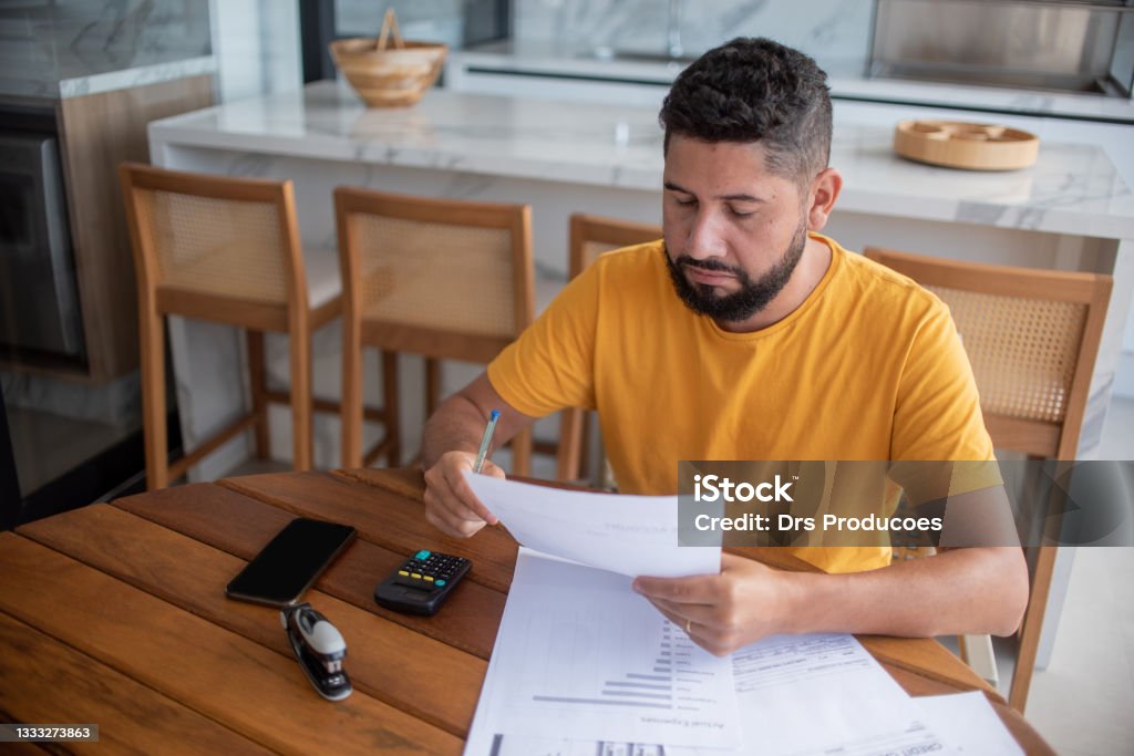 Man calculating debts Man calculating debts at home on the porch, wearing a yellow t-shirt. Debt Stock Photo