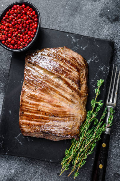 istock Grilled flank beef meat steak on a marble board. Black background. Top view 1333274776