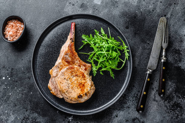istock BBQ Grilled tomahawk pork chop meat steak on a marble board. Black background. Top view 1333274969