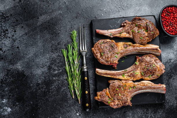 Barbecue fried lamb meat chops on a marble board. Black background. Top view. Copy space Barbecue fried lamb meat chops on a marble board. Black background. Top view. Copy space. plate rack stock pictures, royalty-free photos & images