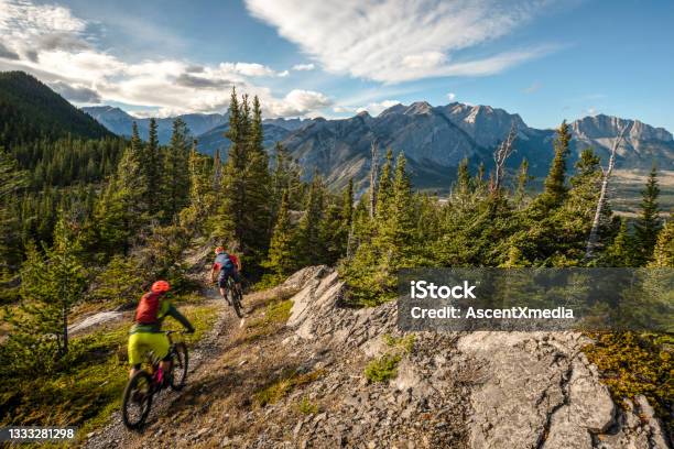 View Of Mountain Bikers Following Trail Down Mountain Stock Photo - Download Image Now