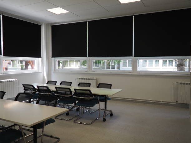 table and chairs in the meeting room in the office, in the classroom or in the library hall. White, black and gray paints in the interior. Black blinds for darkening the room. Modern interior design stock photo