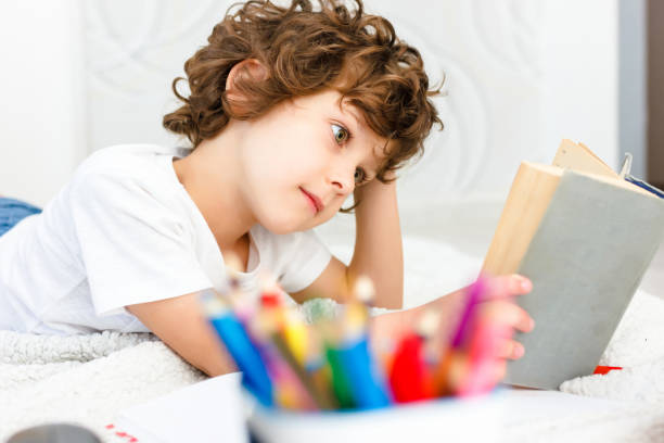 istock Close-up of a curly boy reads a thick book. The student is preparing for testing. 1333292422