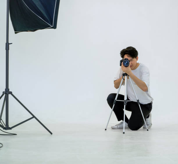 istock Young asian photographer looks through the viewfinder while shooting with the camera. Working atmosphere in the photo studio. 1333301079
