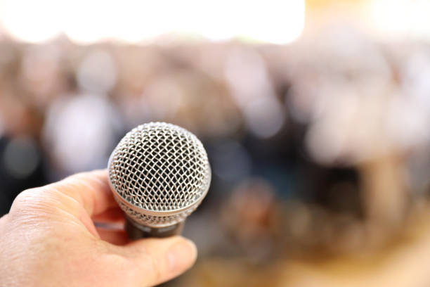 istock Fear of public speaking. A microphone extremely close and audience blurred 1333301299