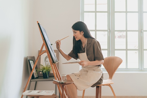 Female Asian painter creating art in her home studio