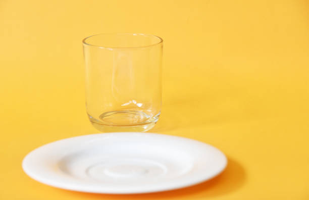 istock Empty small white plate and glass isolated on yellow background 1333310297