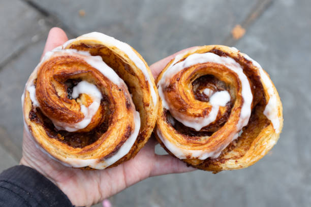 手で持つ2つのおいしいシナモンロール - cinnamon bun icing pastry ストックフォトと画像