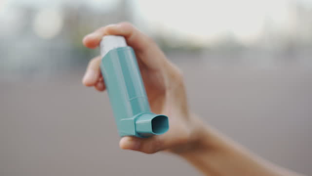 Close up Asian woman using asthma inhaler