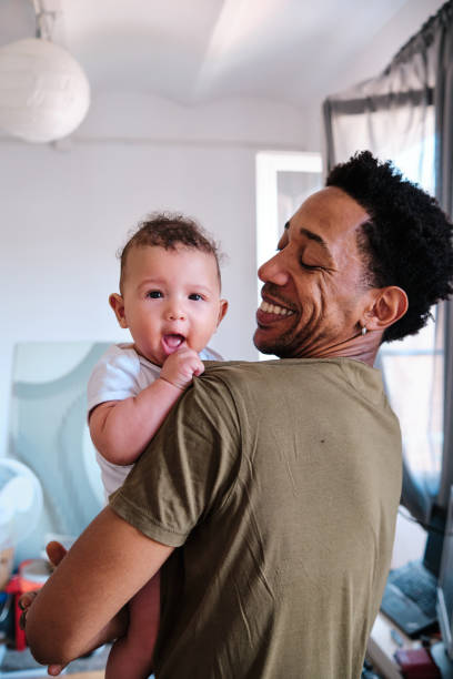 istock Caring man smiling while holding up his baby. 1333318310