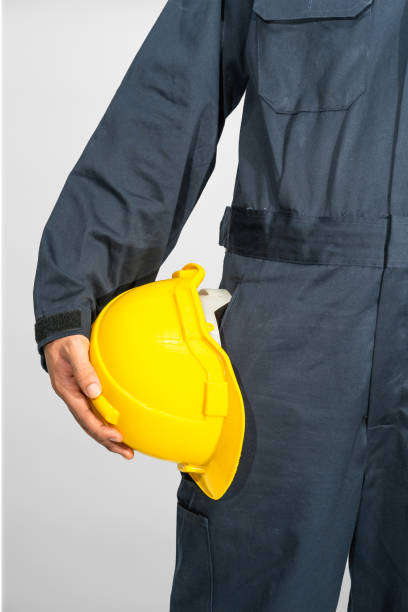 istock Worker standing in blue coverall holding hardhat 1333319338