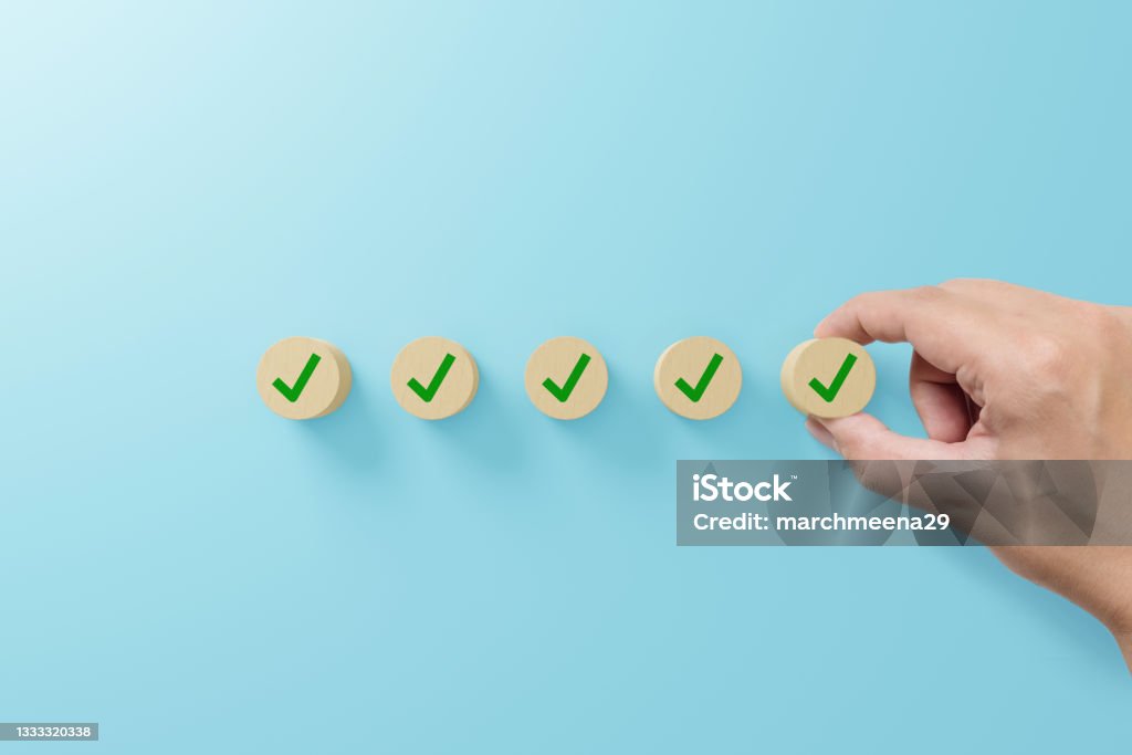 Checklist and check mark concept. Check mark on wooden blocks on light blue background Checklist Stock Photo