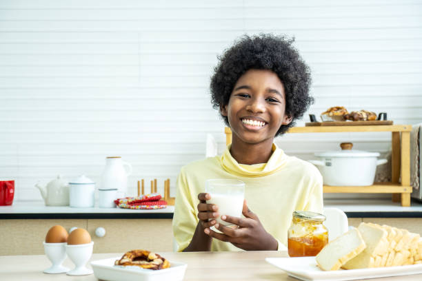 아침 식사를하는 어린이. 행복한 귀여운 아프리카 계 미국인 소년 우유를 마시고 계란빵을 먹고. 아이들은 화창한 아침에 먹는다. 어린 아이들을위한 건강한 균형 잡힌 영양. - eating cereal student human mouth 뉴스 사진 이미지