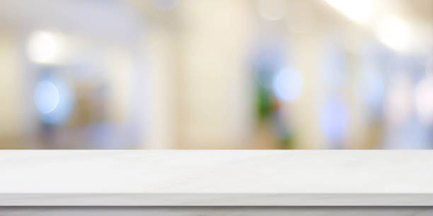 istock Empty white table top, counter, desk over blur perspective store with bokeh light background, White marble stone table, shelf and blurred shop for food, product display mockup, template backdrop, banner, Retail business wallpaper, poster 1333321403