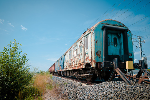 Color image depicting an old train carriage that has been abandoned on the railroad track and left to rust and ruin.