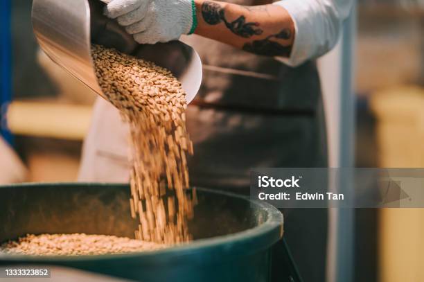 Asian Chinese Working Senior Man Scooping Raw Coffee Beans From Bucket To Weighing Machine And Blending It For Coffee Roasting Process In Factory Warehouse Stock Photo - Download Image Now