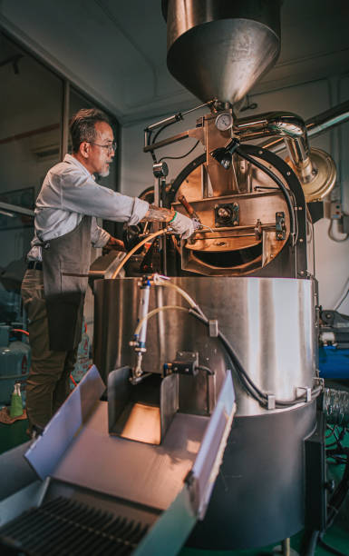 Asian chinese working senior man with glove brushing and cleaning coffee roaster machine with vacuum cleaning Asian chinese working senior man with glove brushing and cleaning coffee roaster machine with vacuum cleaning clean commercial coffee roaster stock pictures, royalty-free photos & images