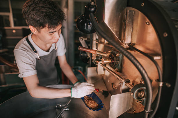 Asian chinese working man hand with glove brushing and cleaning coffee roaster machine Asian chinese working man hand with glove brushing and cleaning coffee roaster machine clean commercial coffee roaster stock pictures, royalty-free photos & images