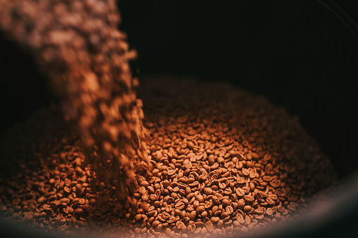 high angle view  pouring raw coffee bean on storage pail with scoop weighting and blending