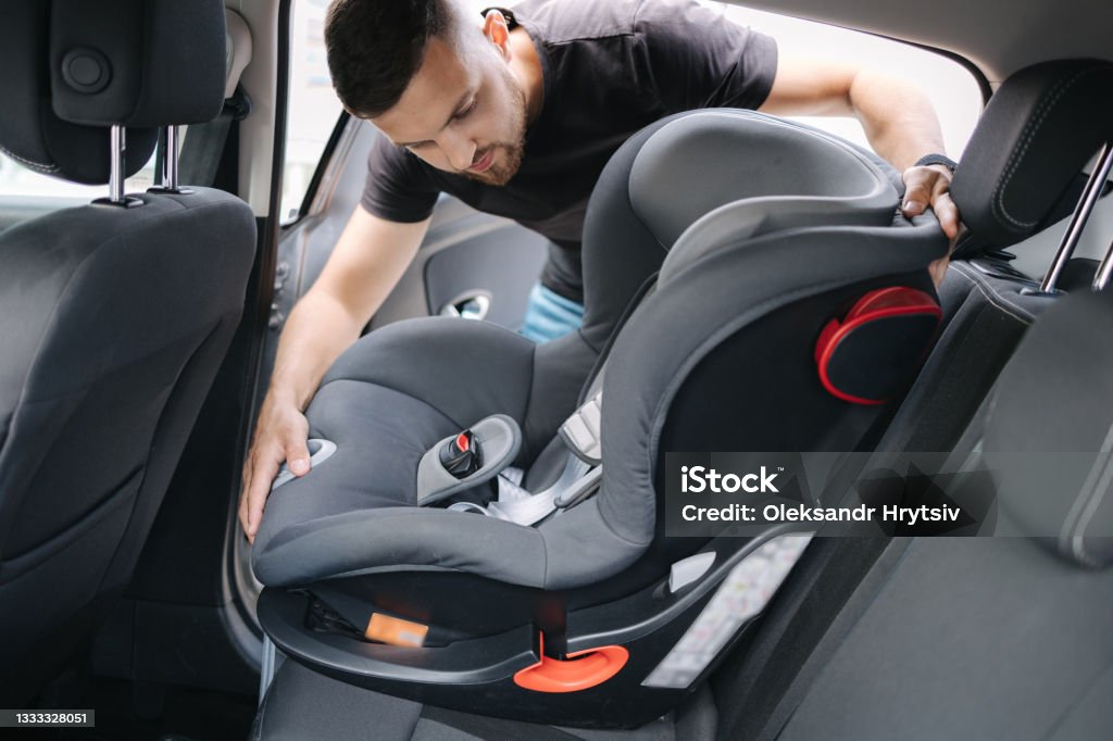 Man installs a child car seat in car at the back seat. Responsible father thought about the safety of his child Man installs a child car seat in car at the back seat. Responsible father thought about the safety of his child. Car Safety Seat Stock Photo