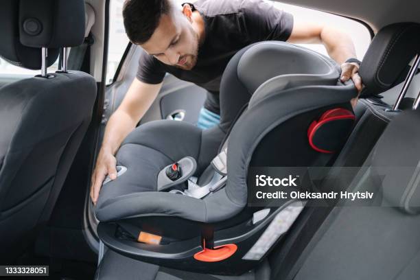 Man Installs A Child Car Seat In Car At The Back Seat Responsible Father Thought About The Safety Of His Child Stock Photo - Download Image Now
